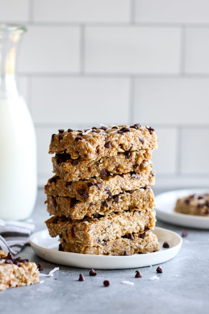 A tall stack of homemade chewy chocolate chip granola bars on a white plate