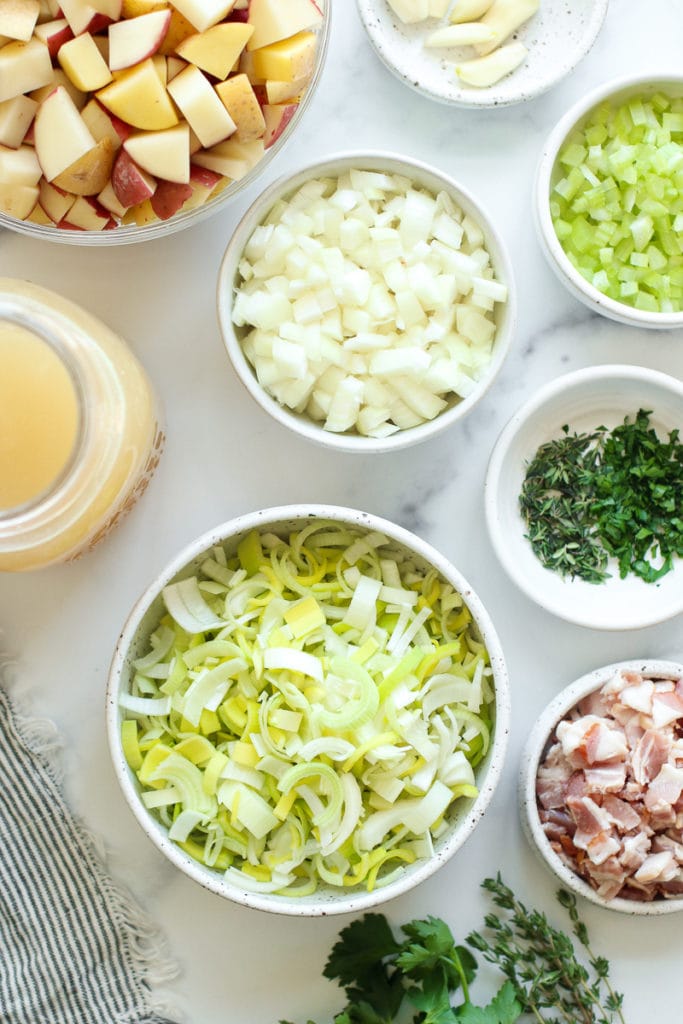 All ingredients for creamy potato leek soup in small bowls and jars.