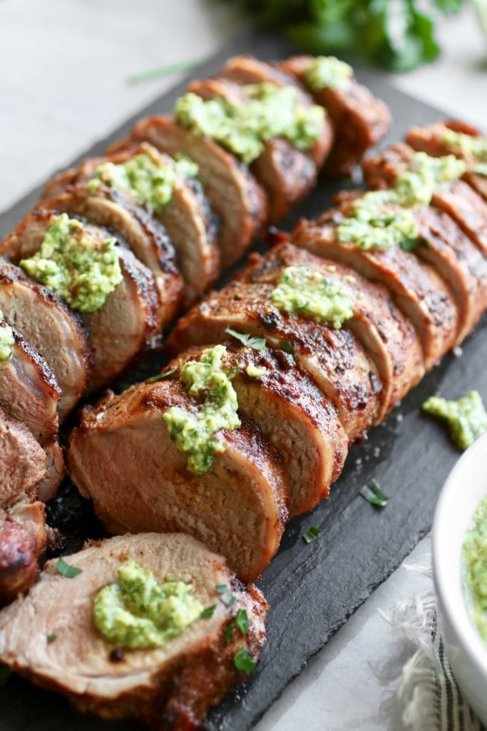 烤豬里脊肉照片用終極燒烤擦調味，並淋上鱷梨綠醬。