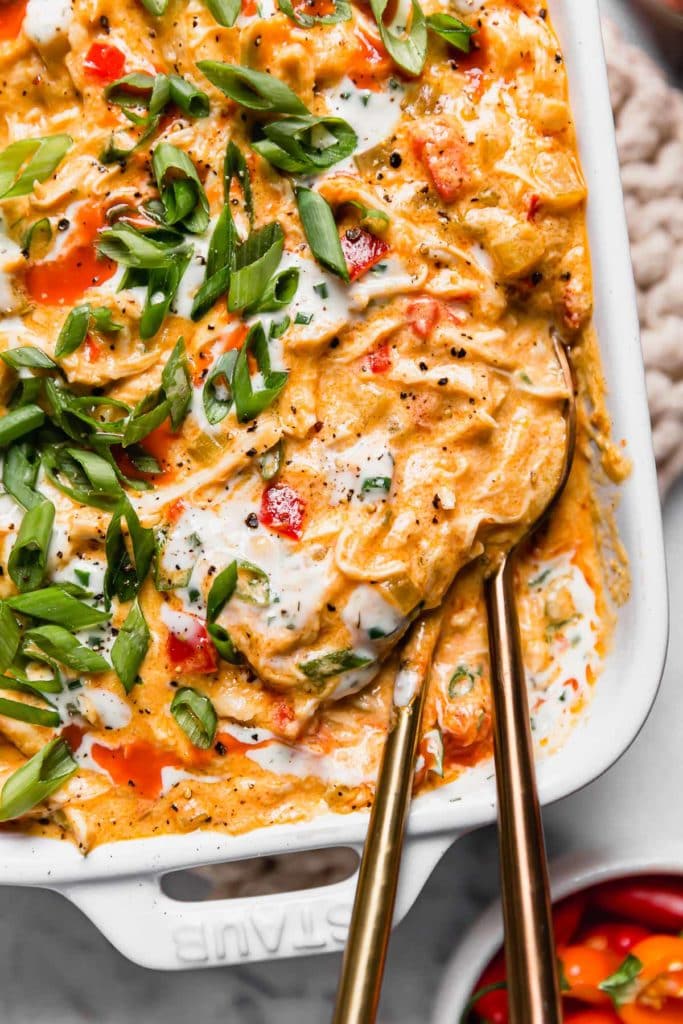 Crockpot Buffalo Chicken in a white serving dish with gold serving utensil. One of the 30 Whole30 Appetizers recipes.