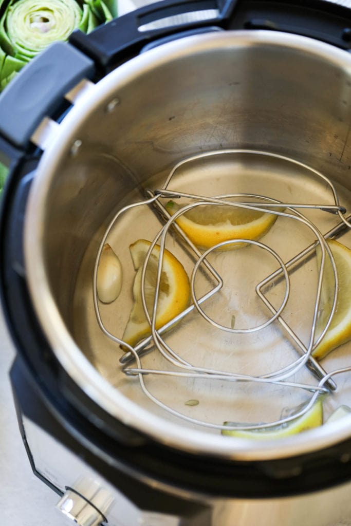 Water, garlic, and lemon wedges in the bottom of an Instant Pot