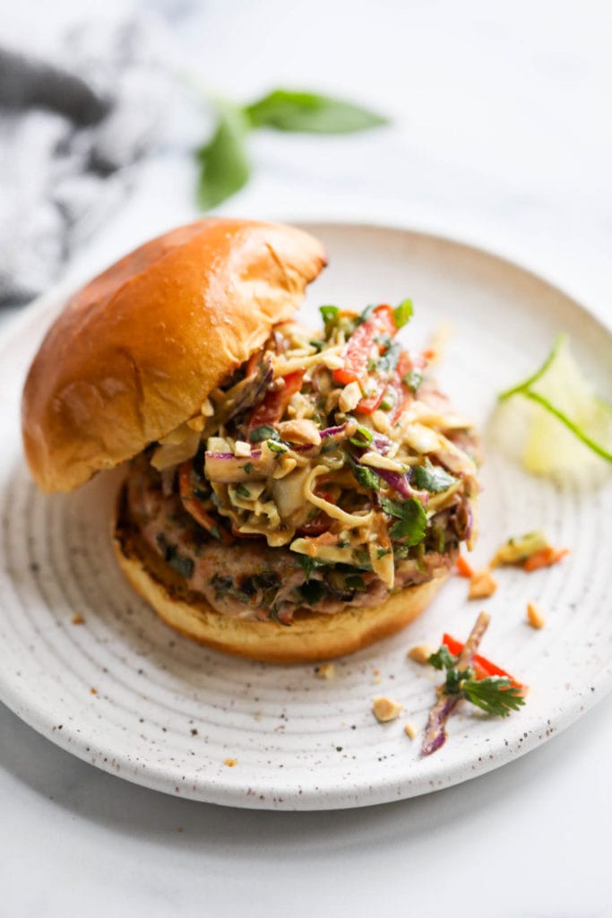A grilled pork burger topped with creamy Thai slaw on a toasted gluten-free bun