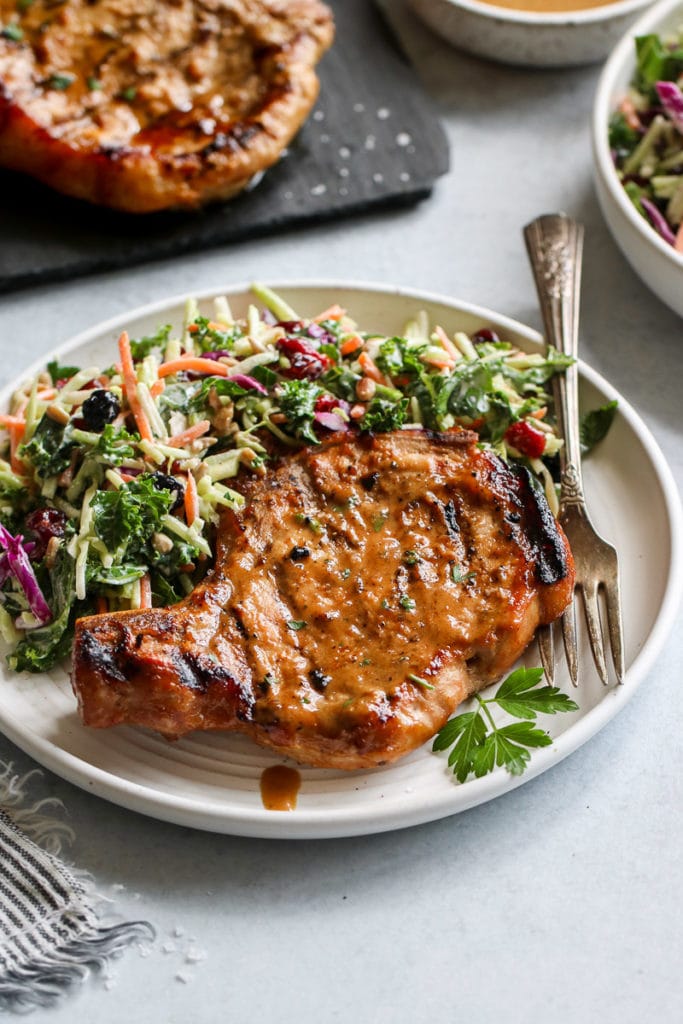Marinated grilled pork chop on a plate with coleslaw on the side. 