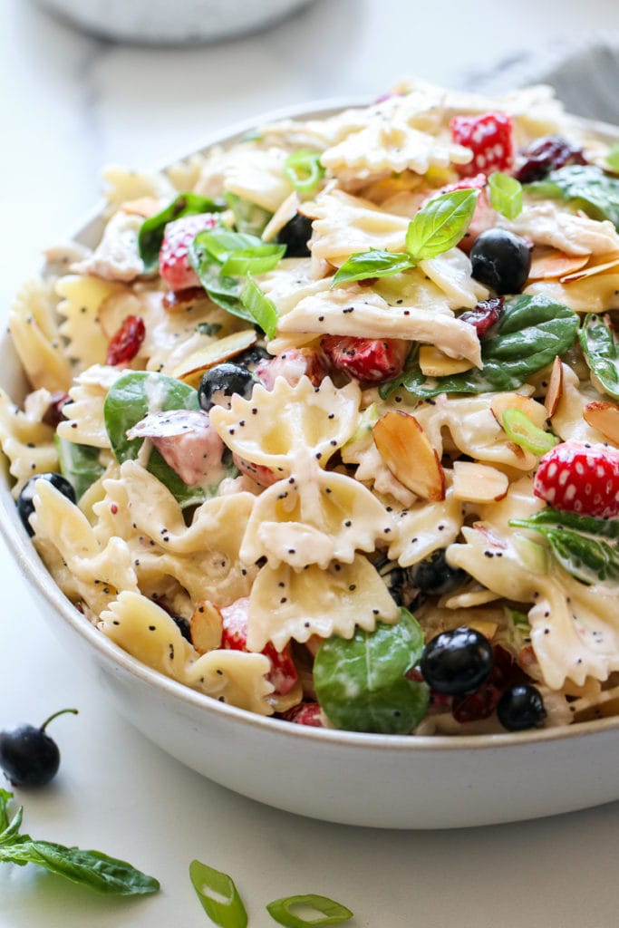 Summer Pasta Salad with Chicken Berries in a white serving bowl garnished with fresh basil. 