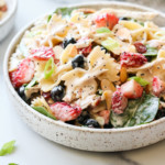 Creamy bow-tie noodle pasta mixed with shredded chicken, fresh berries, baby spinach, and creamy lemon poppy seed dressing in a low profile bowl