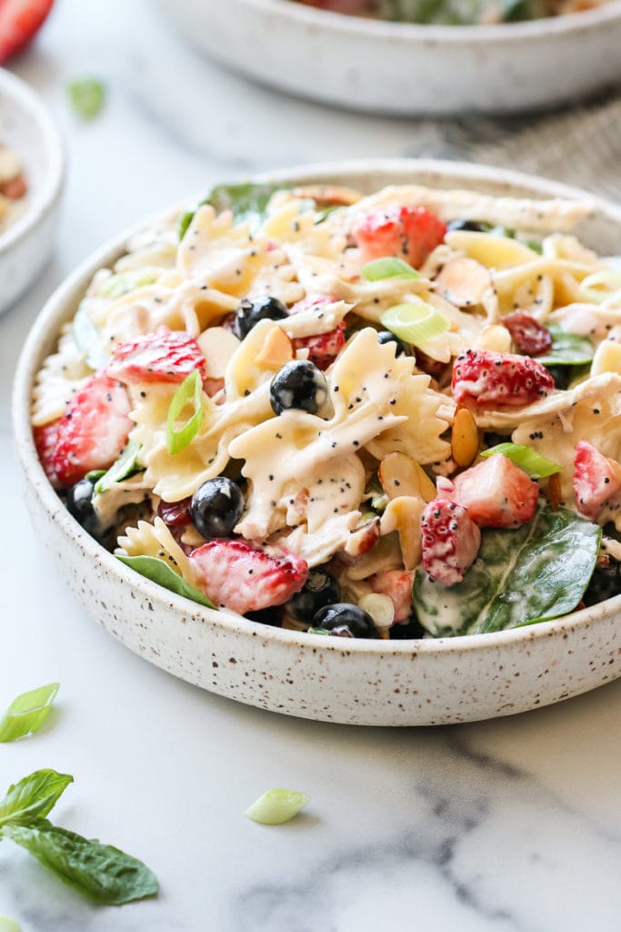 Summer Pasta Salad with Chicken and Berries in a speckled, white, shallow, stoneware bowl.
