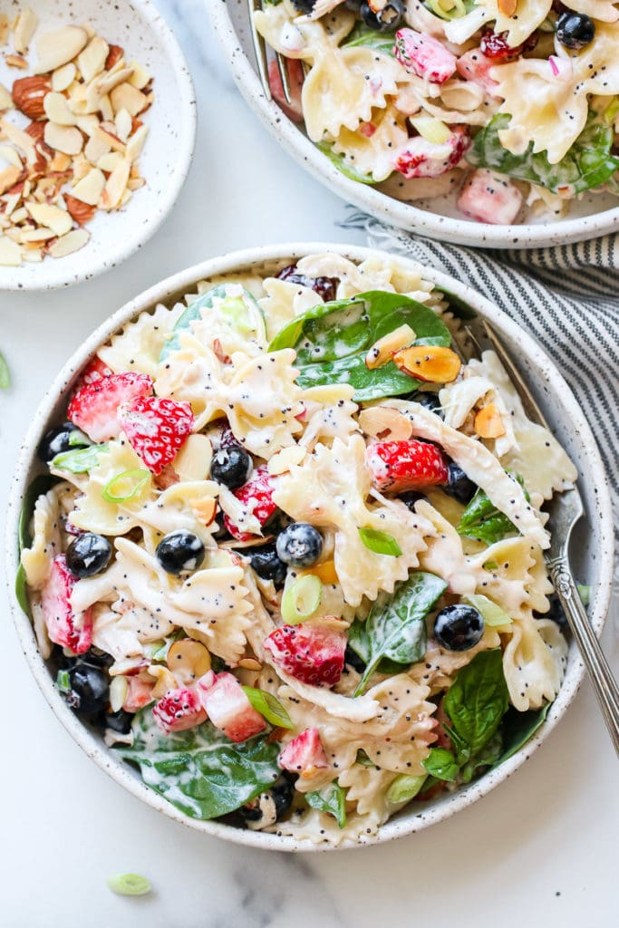 Summer Pasta Salad with Chicken and Berries in a speckled, white, shallow, stoneware bowl.