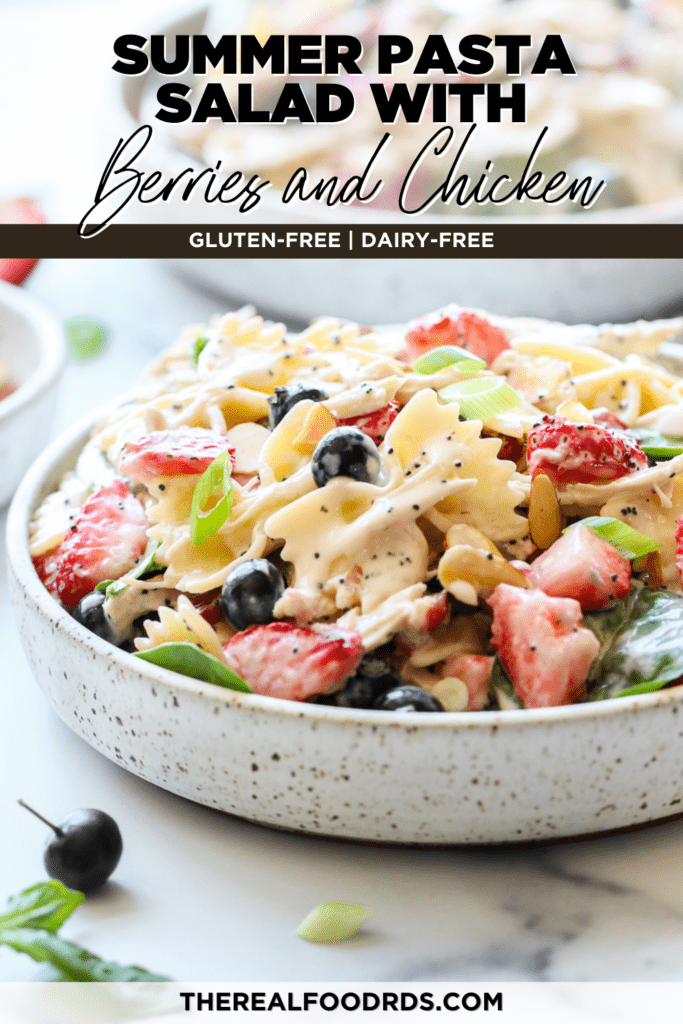 Creamy pasta salad with fresh berries and chicken in a speckled bowl topped with poppy seed dressing